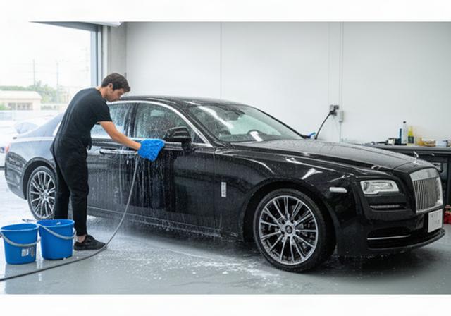 宜野湾の施工スペースで黒い高級車を丁寧に手洗いするスタッフ